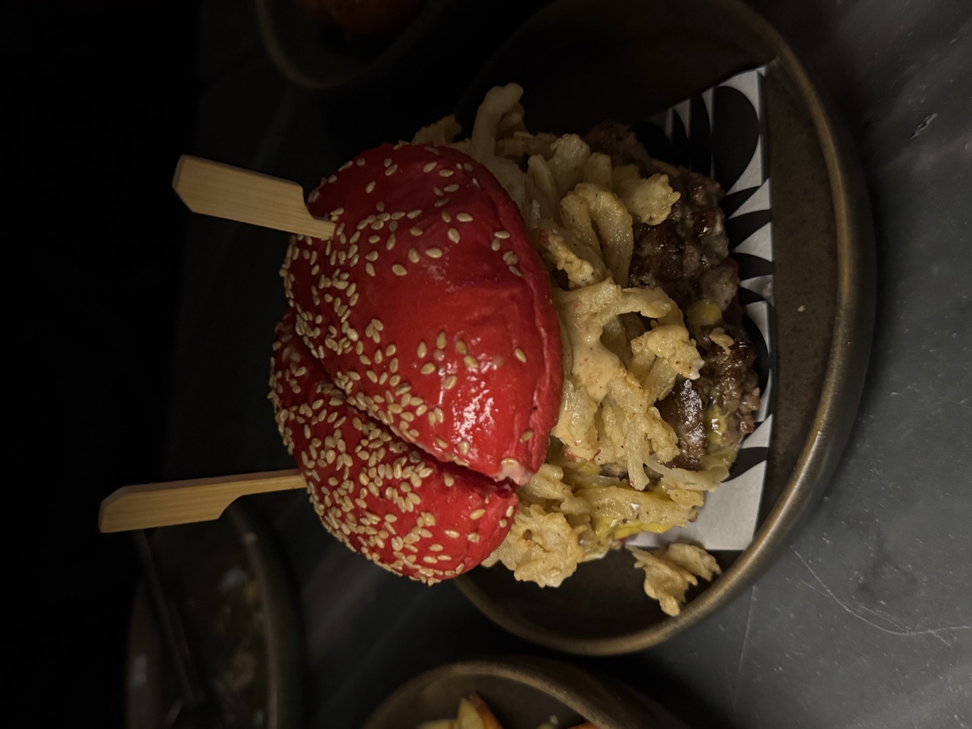 A burger with a red sesame bun, photographed by Mazin