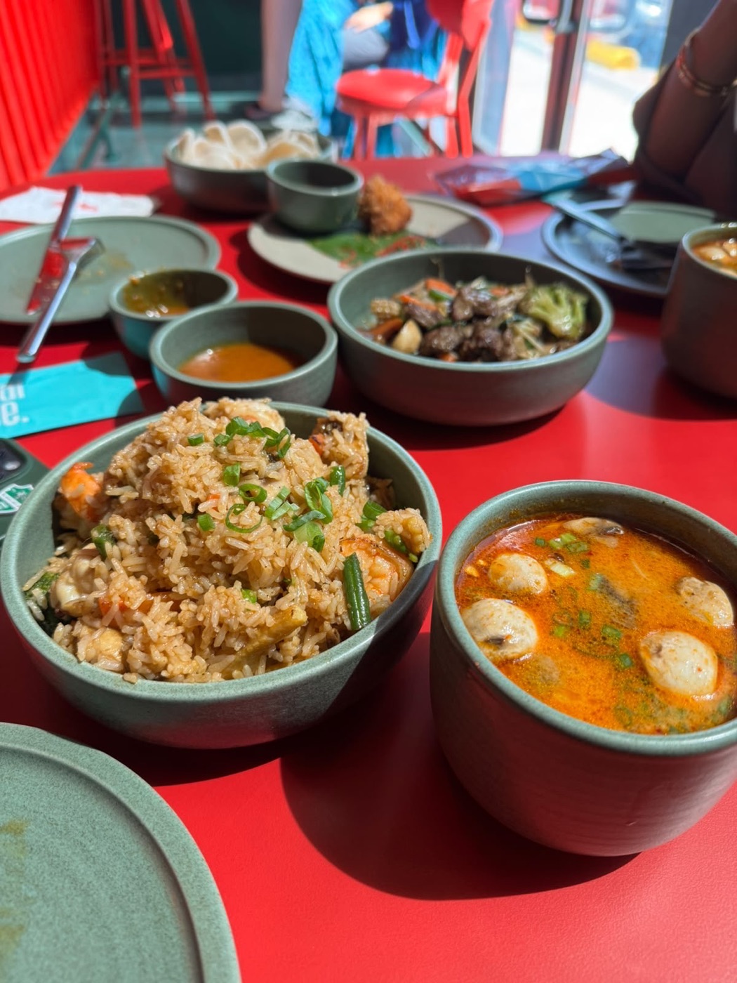 Bowls of rice and soup on a bright red table, photographed by Mazin